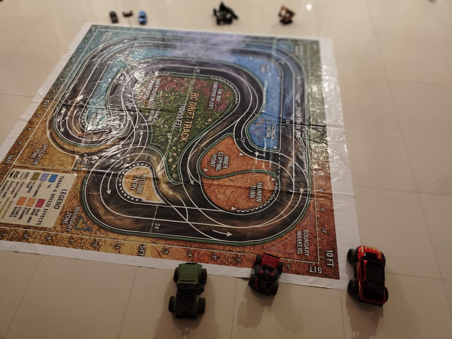 Toy cars race on a detailed RC drift track mat, with a legend and boundary markers visible.