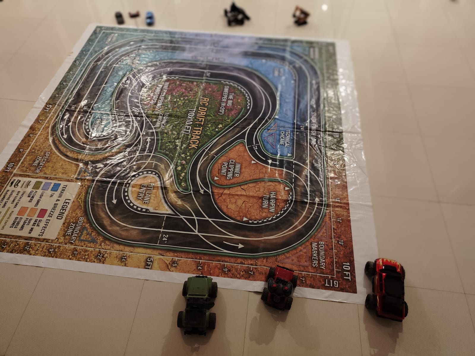 Toy cars race on a detailed RC drift track mat, with a legend and boundary markers visible.