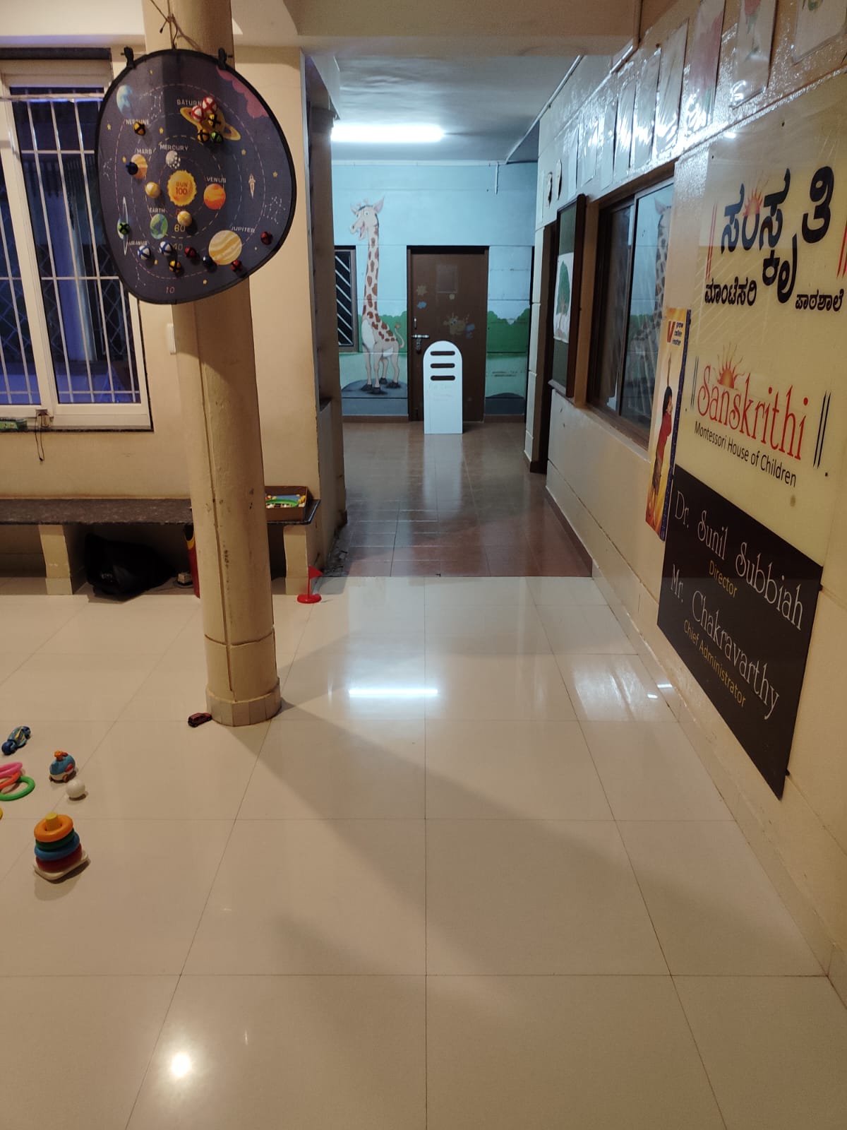 A hallway in a children's center with a solar system display and giraffe murals.