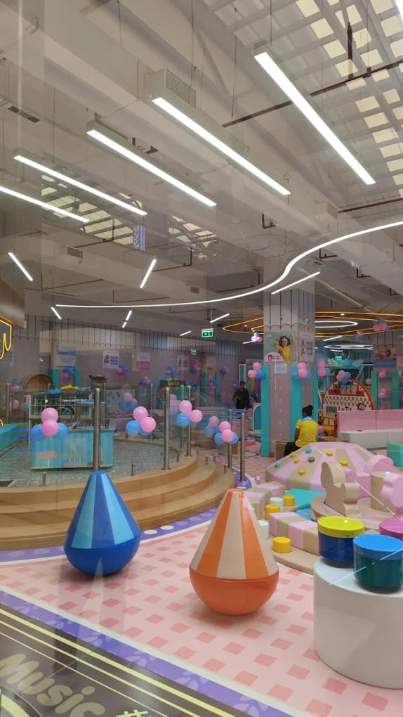 A colorful indoor playground with children playing and adults supervising.