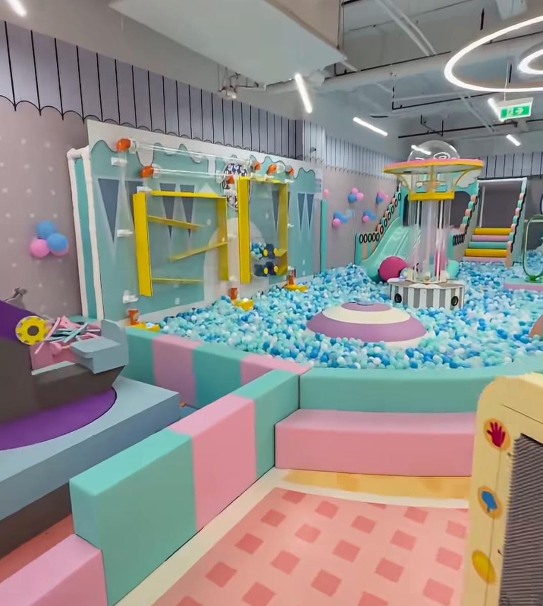A colorful indoor playground with a ball pit, slides, and climbing structures for young children.