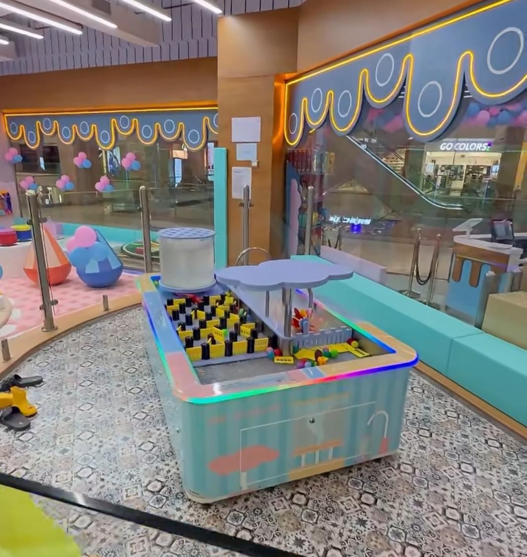 A colorful indoor play area for children with a ball pit and interactive game.
