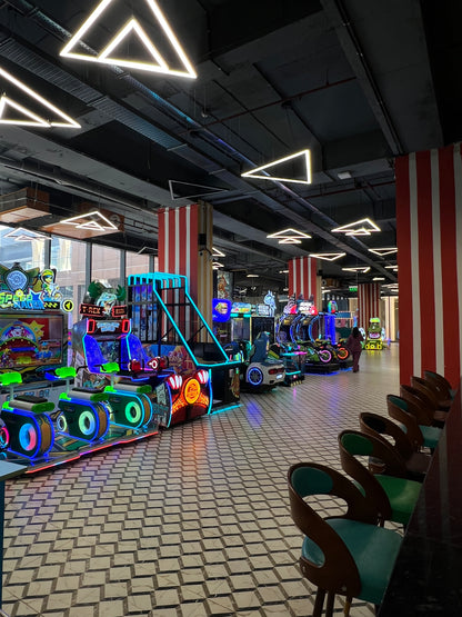 An arcade with rows of colorful racing games and a person walking away.