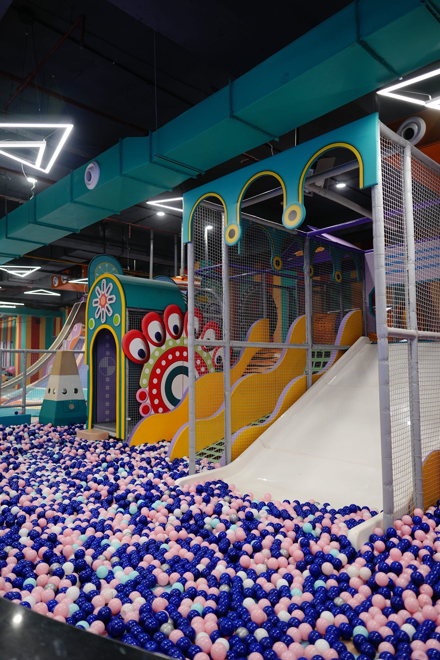 A colorful indoor playground with a ball pit and slides for children.