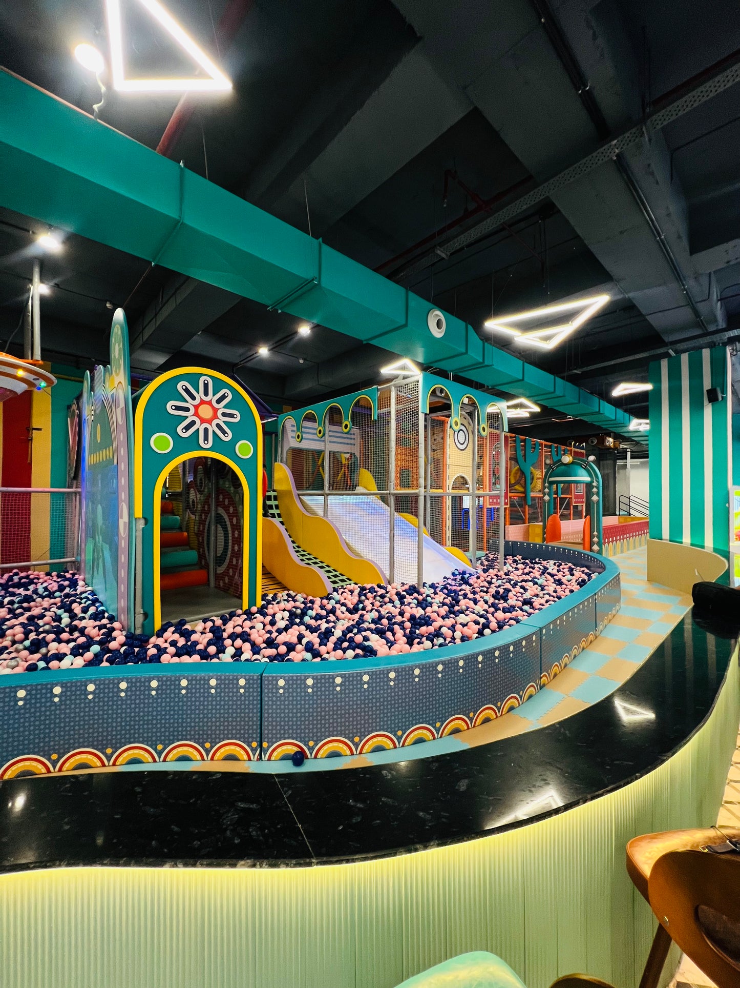 A colorful indoor playground with a ball pit and slides, designed for children.
