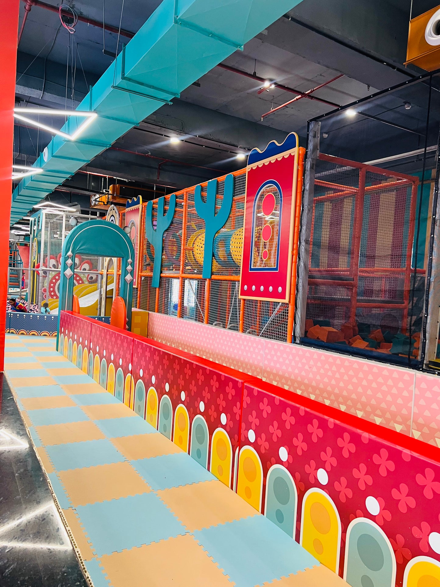 A colorful indoor playground with soft flooring and climbing structures for children.