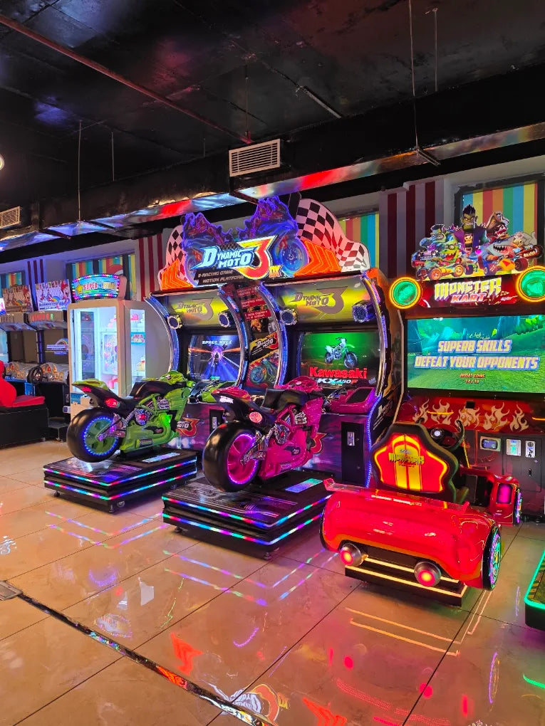 Arcade with motorcycle and car racing games, lit with neon lights.