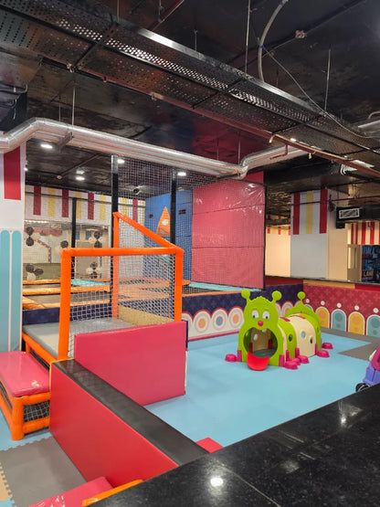 A colorful indoor playground with soft play structures and trampolines for children.