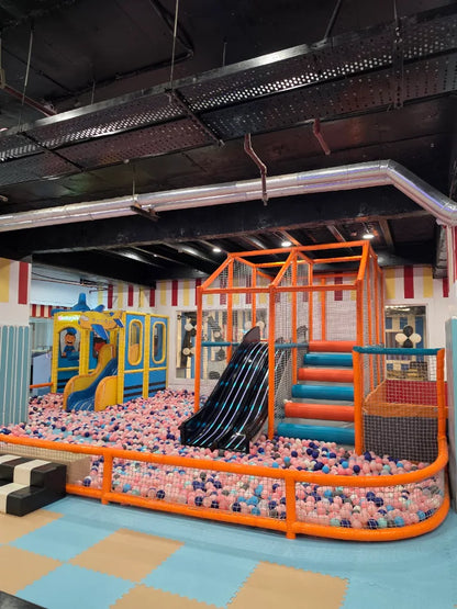 A colorful indoor playground with a ball pit, slides, and climbing structures for children.
