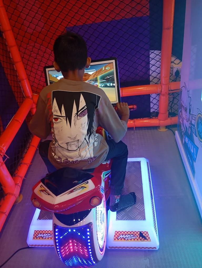 A young boy plays a motorcycle racing arcade game in an indoor play area.