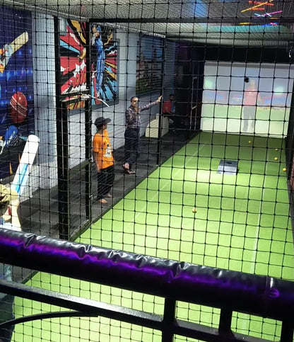 People in a cricket batting cage with a projection screen.
