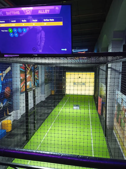 A virtual reality cricket batting cage with a screen showing game stats and a green turf field.