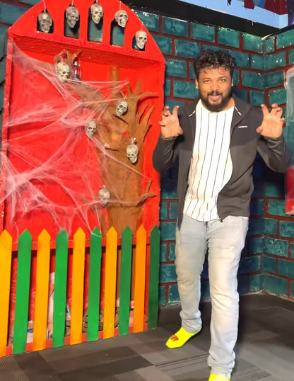 A man in a Halloween-themed setting with skulls and spiderwebs.