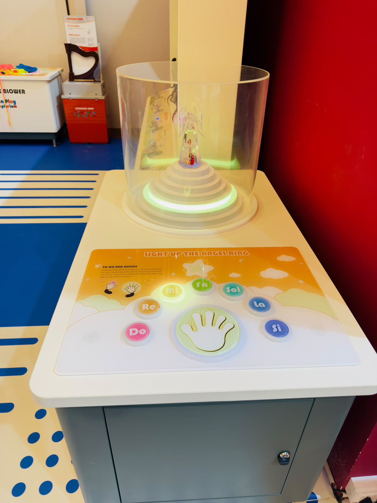 Interactive musical display with colorful buttons and an angel figurine, likely for children.