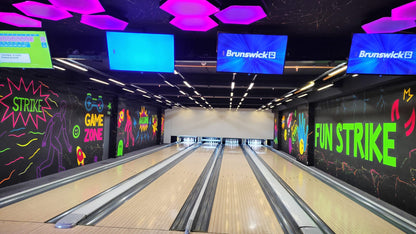 A bowling alley with colorful murals and screens displaying "Brunswick B" and "Fun Strike."