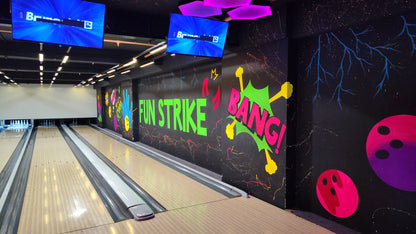 A bowling alley with neon graffiti and screens displaying "Brunswick".