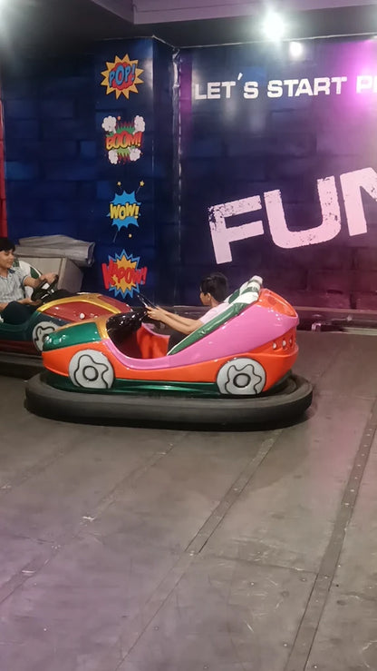 Children enjoying colorful bumper car rides inside a lively indoor amusement area with playful wall designs