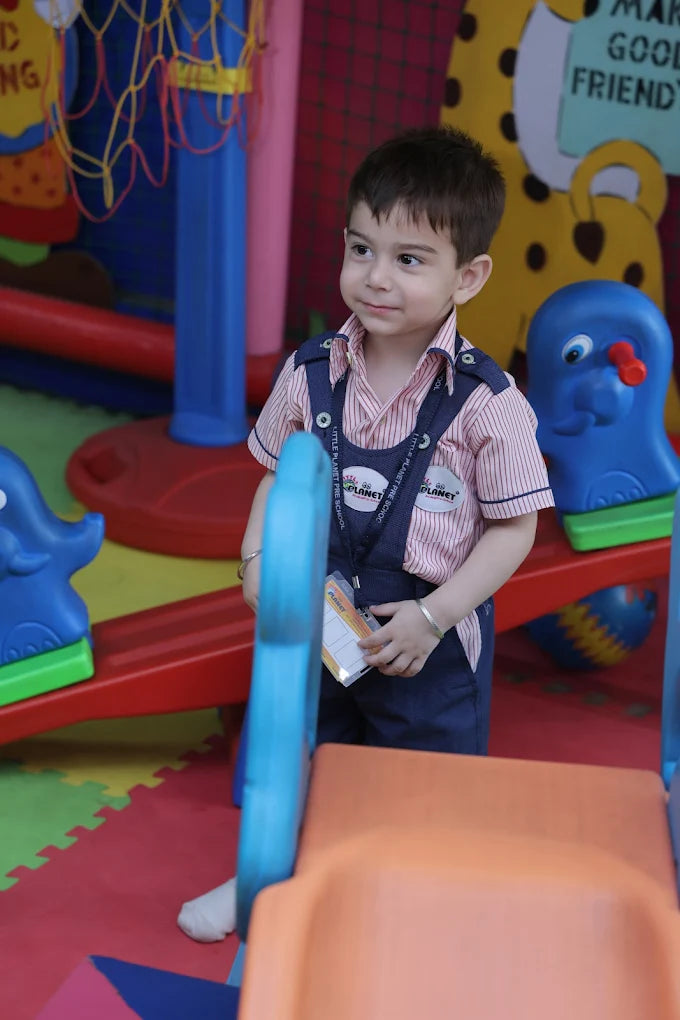 Toddler standing near a blue seesaw with colorful play mats and playful equipment in a cheerful indoor play area