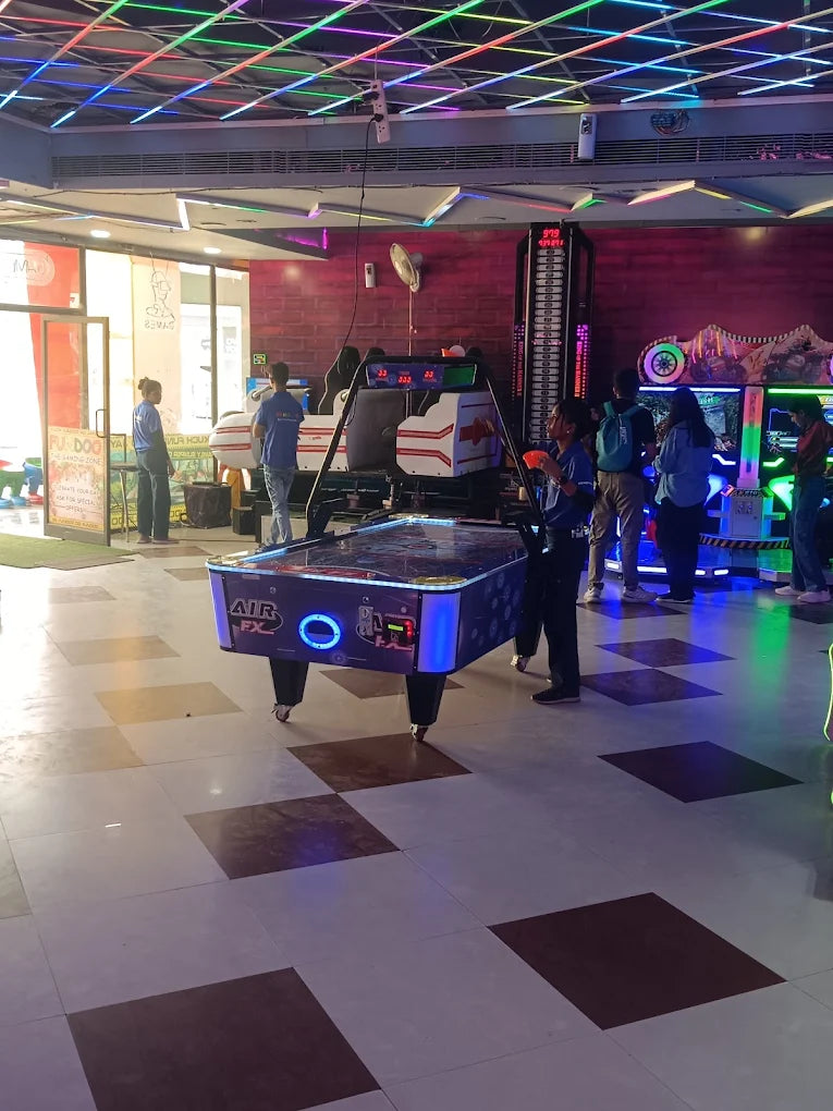 Indoor gaming zone with air hockey table and arcade machines under colorful LED ceiling lights