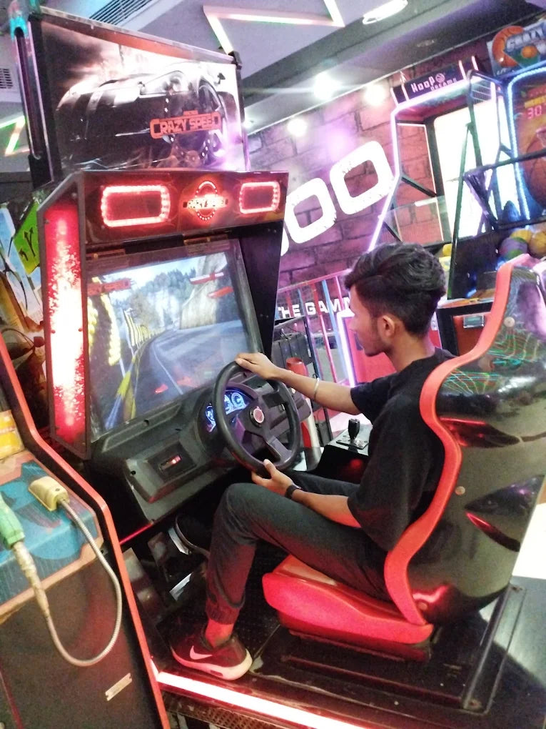 Teen playing an immersive racing arcade game in a vibrant indoor gaming center with neon lighting