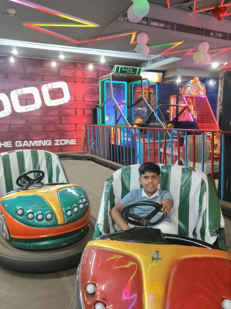 Child enjoying a ride in a colorful bumper car inside a lively indoor gaming zone with vibrant neon lights