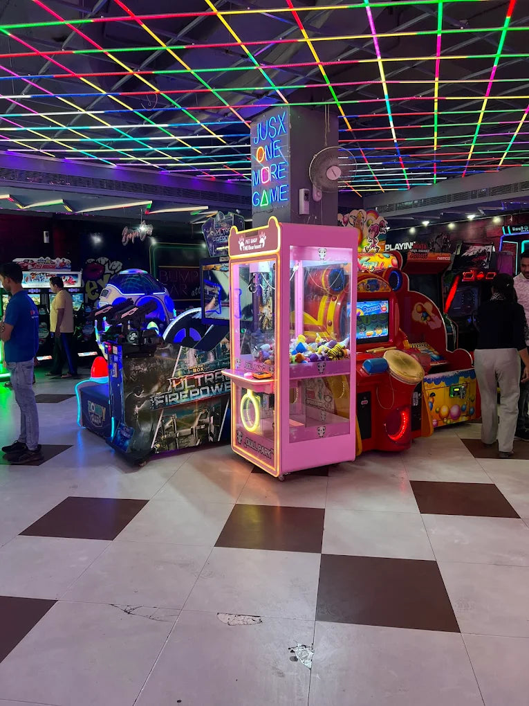 Indoor gaming arcade with neon-lit claw machine, racing simulators, and colorful arcade games in a lively entertainment space