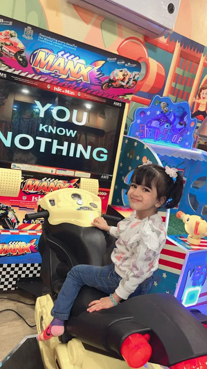 Child sitting in a video game chair with a colorful arcade machine in the background