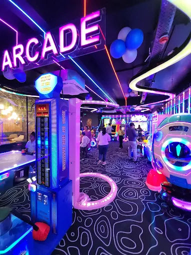 An arcade with neon lights and people playing games.