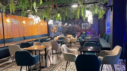 A modern cafe with lush greenery hanging from the ceiling and stylish seating.