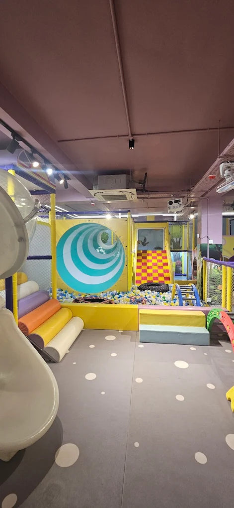 A colorful indoor playground with a ball pit, slides, and climbing structures for young children.