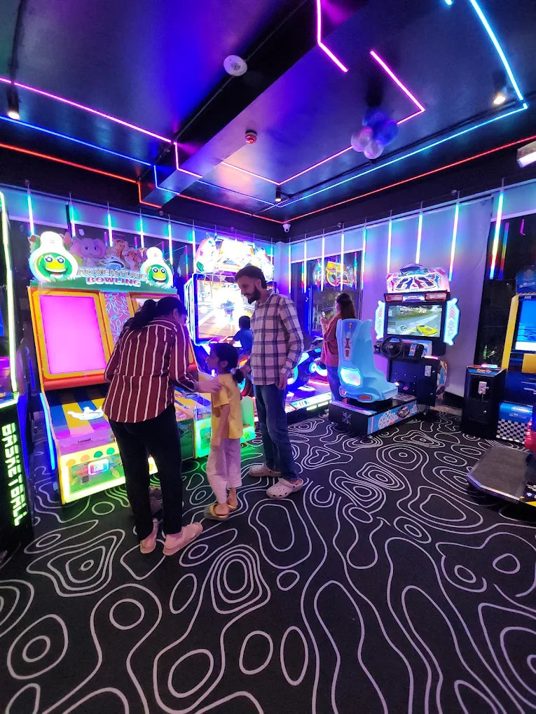 A family plays at an arcade with colorful lights and video games.