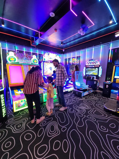 A family plays at an arcade with colorful lights and video games.