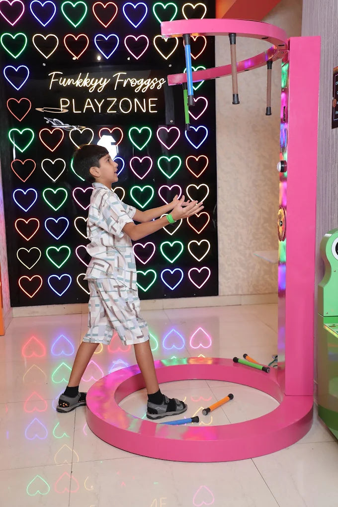 Child playing on a colorful play structure with heart-shaped lights in the background.