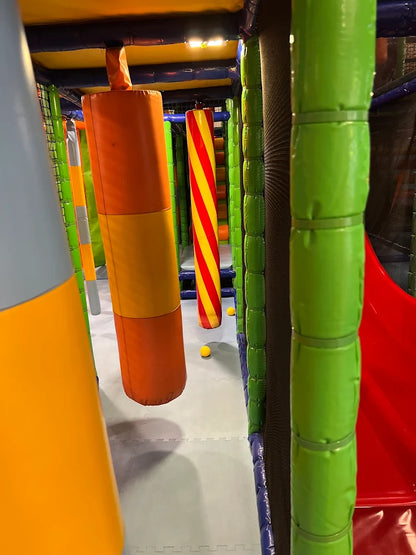 A colorful indoor playground with soft obstacles and a red slide.