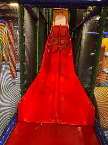 A bright red double slide in a children's indoor play area.