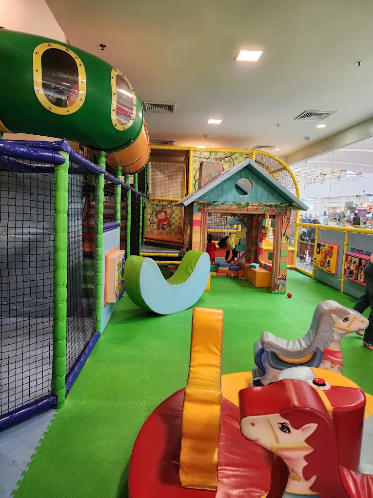 A colorful indoor playground with soft play structures and a small playhouse for children.
