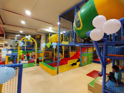 Children play in a colorful indoor playground with slides and climbing structures.