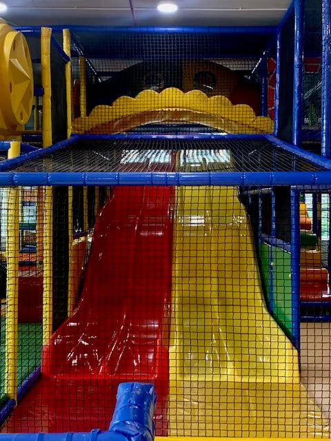 A colorful indoor playground with red and yellow slides for children.