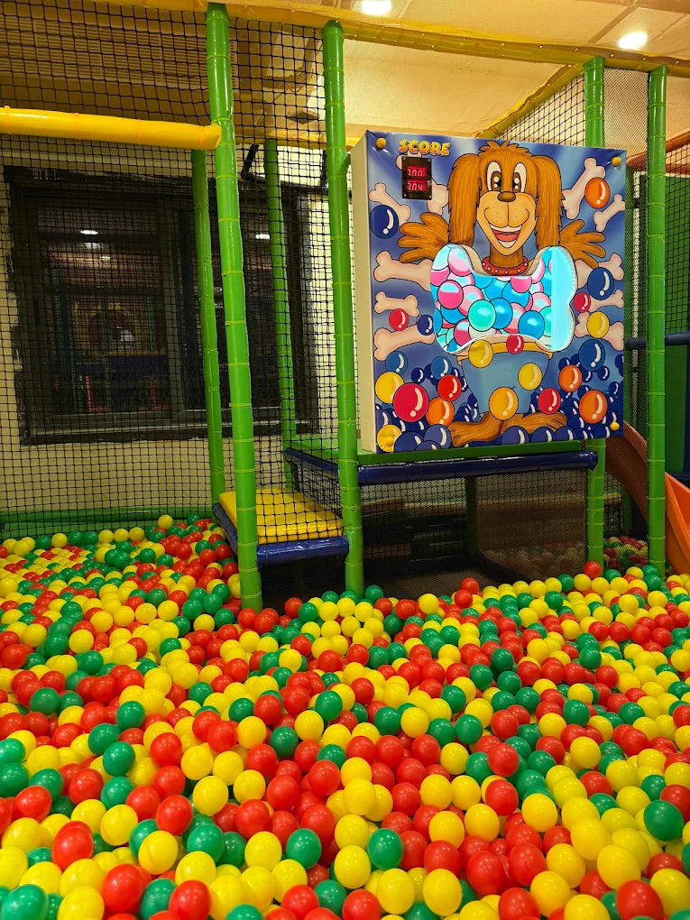 A ball pit filled with colorful balls, with a game board featuring a cartoon dog.