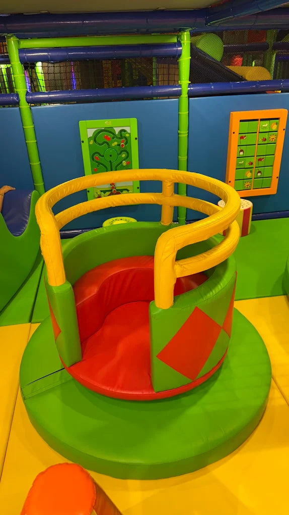 A colorful soft play area for children with a spinning seat and maze games.