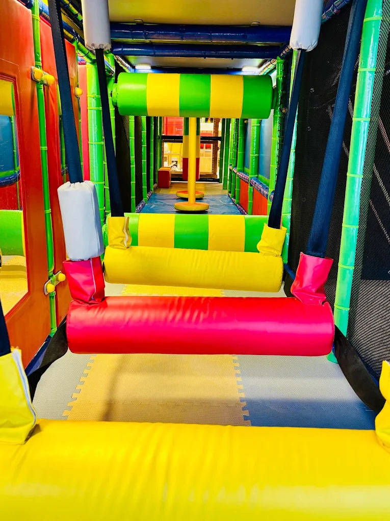 A colorful indoor playground with soft obstacles and swings for children.