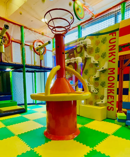 A colorful indoor playground with a red and yellow climbing structure and a "Funky Monkeys" wall.