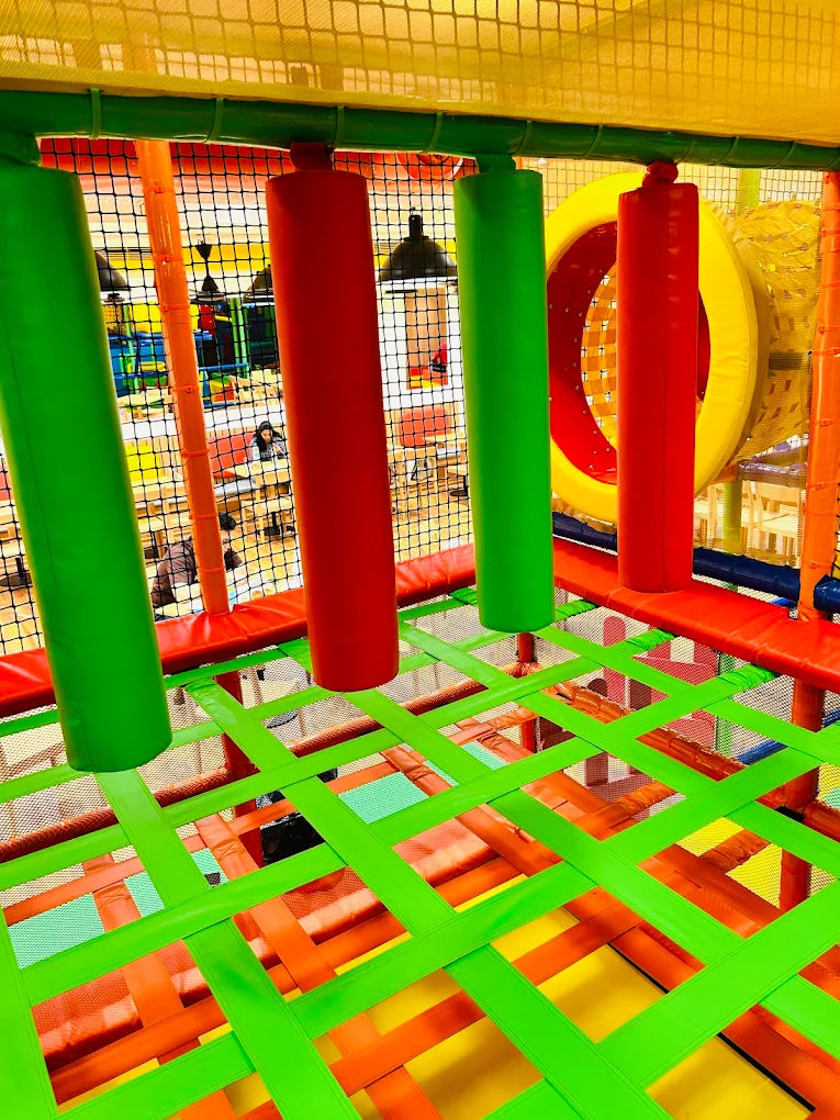 Indoor playground with colorful climbing structures and nets for children.
