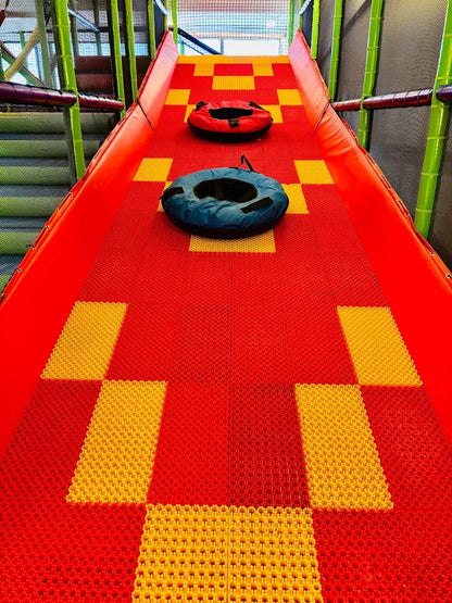 Two inflatable tubes sit on a red and yellow checkered slide in a children's play area.