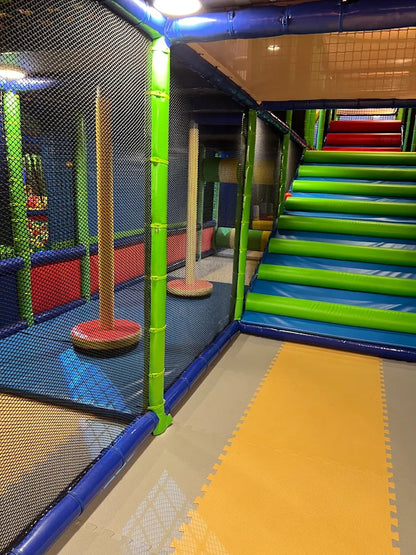A colorful indoor playground with soft mats, netting, and a large slide.