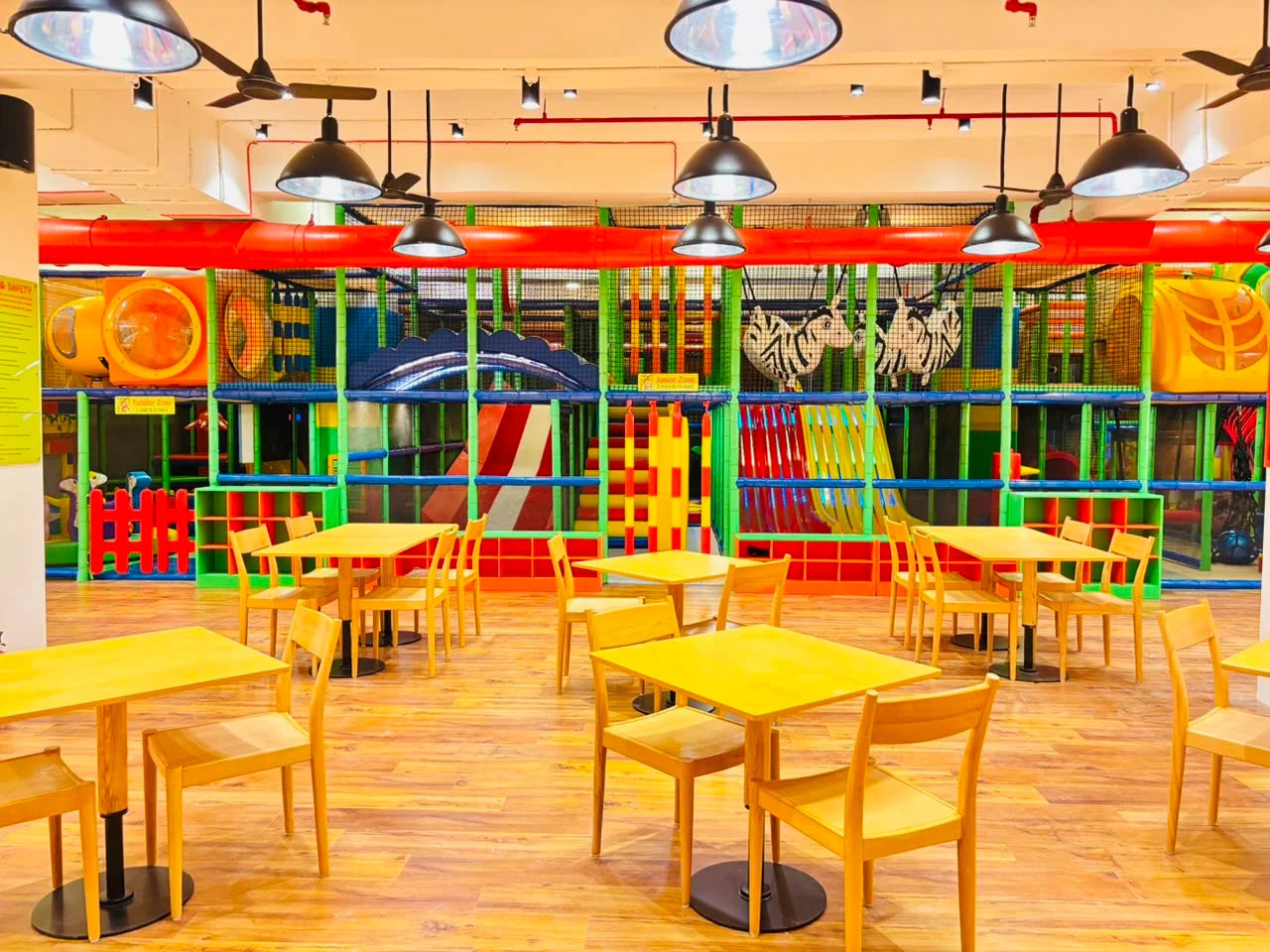 A colorful indoor playground with tables and chairs in the foreground.