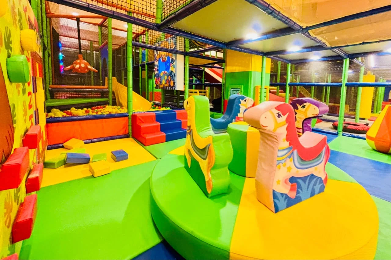 A colorful indoor playground with soft play structures and a ball pit for young children.