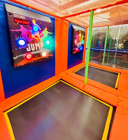 An indoor trampoline park with colorful jump pads and interactive game screens.
