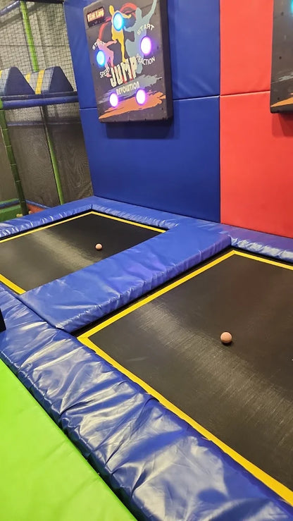 Two trampolines with pink balls on them in a trampoline park.