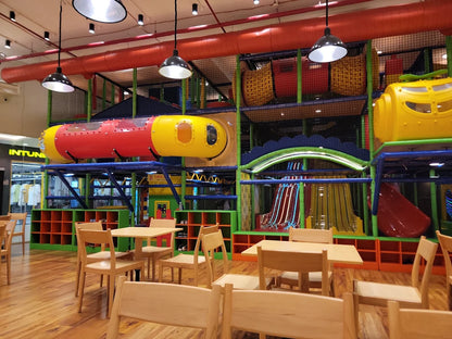 A colorful indoor playground with slides and tunnels, and a seating area for children.